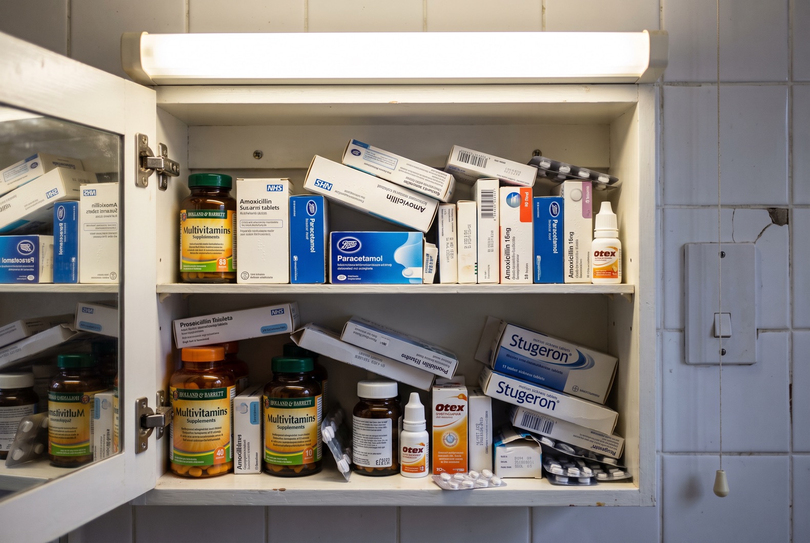 Open medicine cabinet packed with prescription boxes and supplements